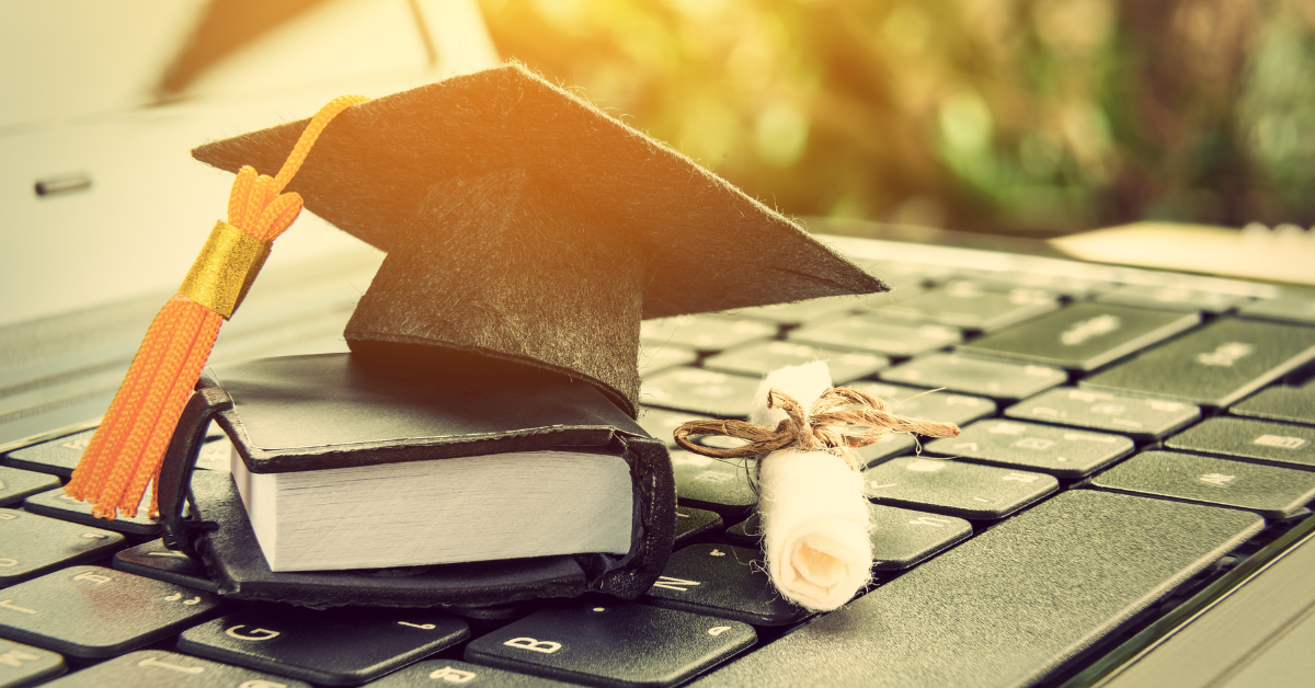 Mini graduation cap and book on keyboard